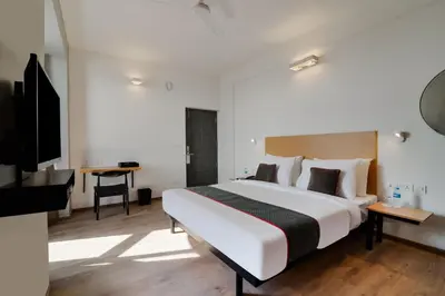 a hotel room with a large bed and a television at Super Townhouse Srm Kuppakonam Pudur in Coimbatore