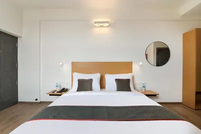 a bedroom with a large white bed and a mirror at Super Townhouse Srm Kuppakonam Pudur in Coimbatore
