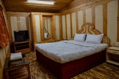 a bedroom with a large bed and a television at JJS Cottages in Coonoor