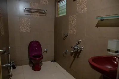 a bathroom with a red toilet and a sink at JJS Cottages in Coonoor