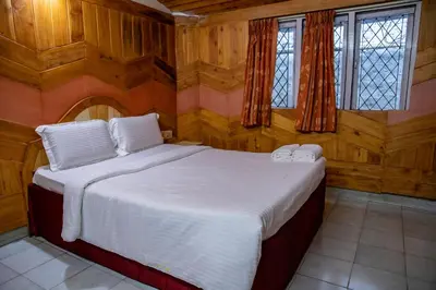 a bedroom with a bed with wooden walls and windows at JJS Cottages in Coonoor