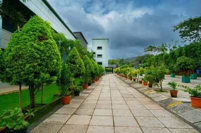 a walkway lined with trees in front of a building at The Sanihara Hotel & Resort in Vythiri