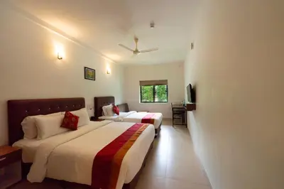 a hotel room with two beds and a television at The Sanihara Hotel & Resort in Vythiri