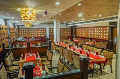a dining room with wooden tables and chairs at Hotel Sidhartha Chalakudy in Kizhake Chālakudi