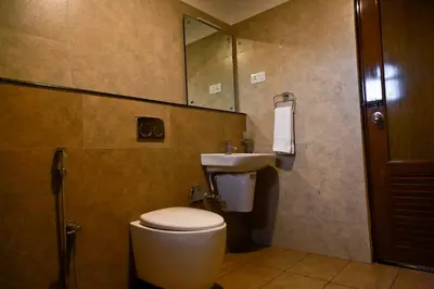 a bathroom with a toilet and a sink and a mirror at KB RESIDENCY in Kozhikode