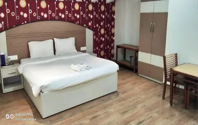 a bedroom with a large white bed and a table at DEW DROP INN in Ooty