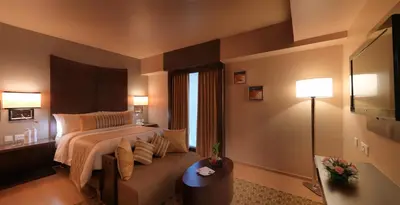 a hotel room with a bed and a couch at The Quorum in Mysore