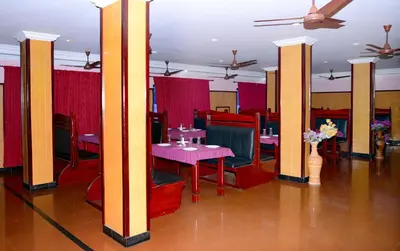 a restaurant with tables and chairs and a ceiling fan at Hotel Kairali in Palakkad