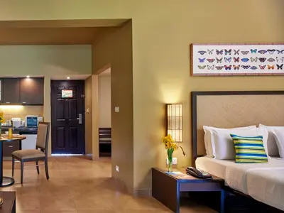 a hotel room with a bed and a kitchen at Club Mahindra Virajpet, Coorg in Virajpet