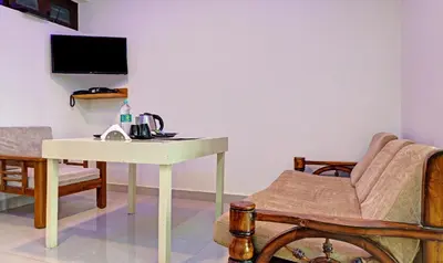a living room with a table and a chair and a desk at Treebo New Redfern, Madikeri in Madikeri