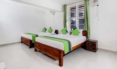 two beds in a room with white walls at Treebo New Redfern, Madikeri in Madikeri