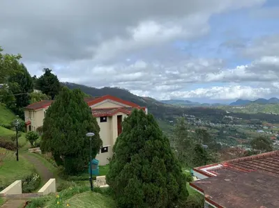 a group of trees in front of a house at Mountain Retreat - A Hill Country Resort in Ooty
