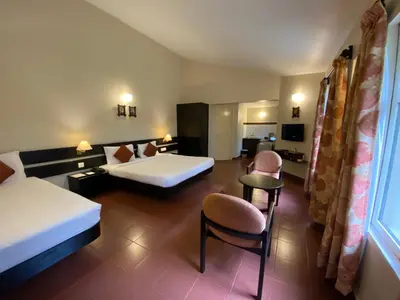 a hotel room with two beds and a table and chairs at Mountain Retreat - A Hill Country Resort in Ooty
