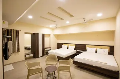 two beds in a room with two chairs and a table at Ponnis Hotel in Palani