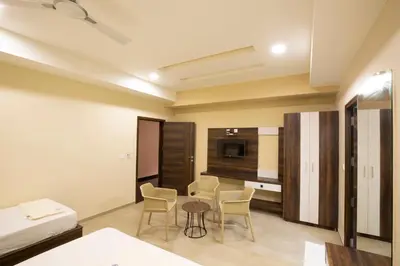 a room with a bed and a table and chairs at Ponnis Hotel in Palani