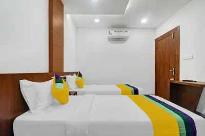 a bedroom with a white bed with colorful pillows at Hotel Fathima Palace in Kottakkal