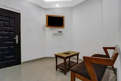 a room with a tv and a chair and a table at Hotel Fathima Palace in Kottakkal