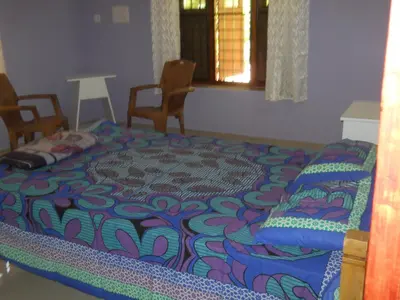 a bed in a room with chairs and a window at CoconutCrazy! Homestay in Ottappālam