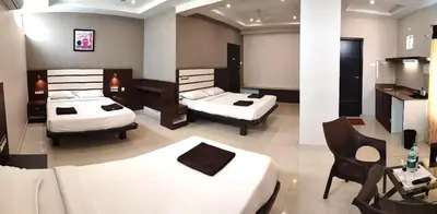 a hotel room with two beds and a desk at Aadya Elite in Mysore