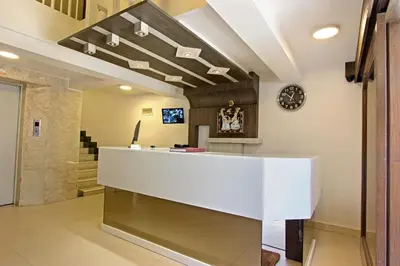 a lobby with a white reception desk and a clock at Mannars Residency in Mysore