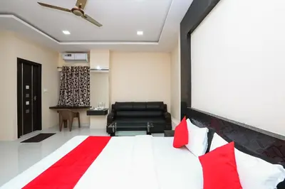 a bedroom with a large bed and a black chair at Suvarna Suits in Mysore