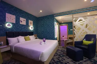 a bedroom with a large bed and a chair at Mintotel Wayanad in Sultan Bathery