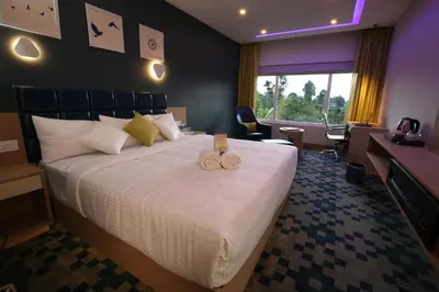 a hotel room with a large bed with two candles on it at Mintotel Wayanad in Sultan Bathery