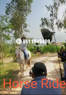 a man taking a picture of a woman riding a horse at Shining Caves Resort in Varagampadi