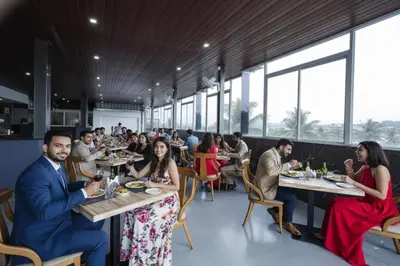 a group of people sitting at tables in a restaurant at FabHotel Prime Suloka Towers - 500m from View point, Kaveri River in Kushālnagar