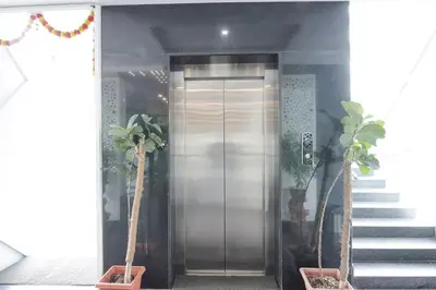 an elevator in a building with two potted plants at FabHotel Prime Suloka Towers - 500m from View point, Kaveri River in Kushālnagar
