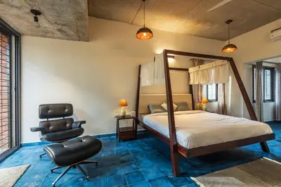 a bedroom with a canopy bed and a chair at SaffronStays Riverstone 3-BR Riverside Villa with Farm Views in Seringapatam