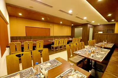 a restaurant with wooden tables and chairs and a podium at Hotel Wilton in Sultan Bathery