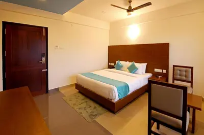 a bedroom with a bed and a table and a desk at Hotel Wilton in Sultan Bathery