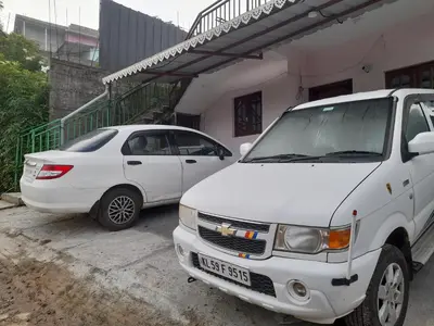 two white cars parked in front of a building at Munnar Brindavan Cottage in Munnar