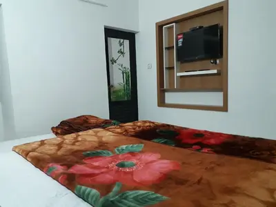a bedroom with a bed with a flower blanket and a mirror at Munnar Brindavan Cottage in Munnar