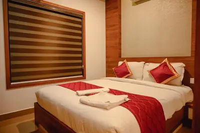 a bedroom with two beds with red pillows and a window at Royal Plaza Wayanad in Vythiri
