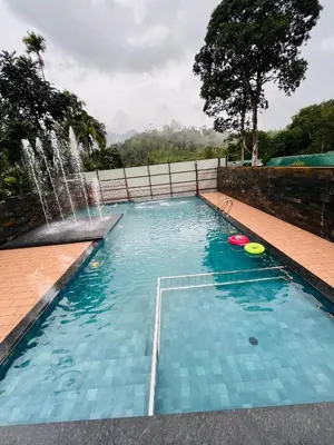 a swimming pool with a fountain and two frisbees at Royal Plaza Wayanad in Vythiri