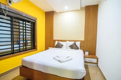 a bedroom with a white bed with yellow walls and a window at Royal Plaza Wayanad in Vythiri