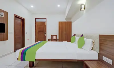 a bedroom with a large white bed with green pillows at Treebo RJ Residency in Mysore
