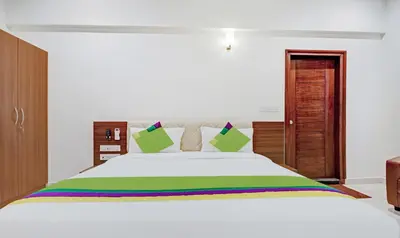 a bedroom with a large white bed with green pillows at Treebo RJ Residency in Mysore