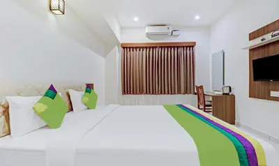 a bedroom with a large white bed with colorful pillows at Treebo RJ Residency in Mysore