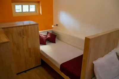 a small room with a bed and a cabinet at Roambay in Mysore