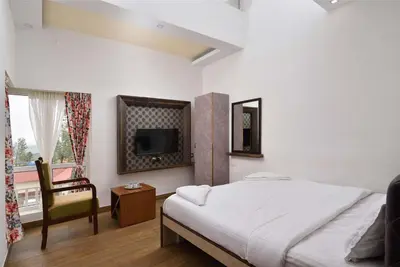 a bedroom with a bed and a tv and a chair at Villa Sullivan by VEO - Part of StayVista in Ooty