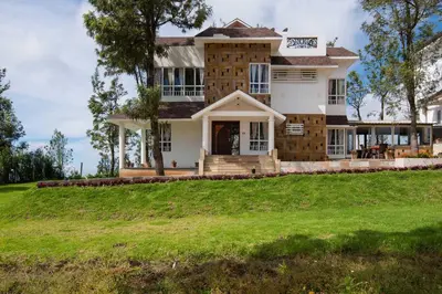a house on a hill with a green yard at Villa Sullivan by VEO - Part of StayVista in Ooty