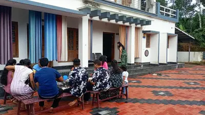 a group of people sitting on a bench outside of a house at Ammu's home stay in Panamaram
