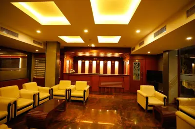 a waiting room with white chairs and a television at Luxora Hotel and Spa in Kozhikode
