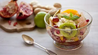 a salad in a glass bowl on a table with a spoon at GAYATHRI HOTELS in Badagara