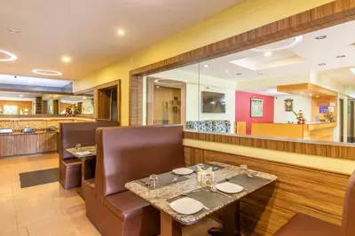 a restaurant with a table and chairs and a bar at Vinayaga Inn by Poppys, Ooty in Ooty