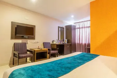 a bedroom with a bed and a desk and a tv at Vinayaga Inn by Poppys, Ooty in Ooty