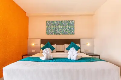 a bedroom with a large white bed with blue pillows at Vinayaga Inn by Poppys, Ooty in Ooty